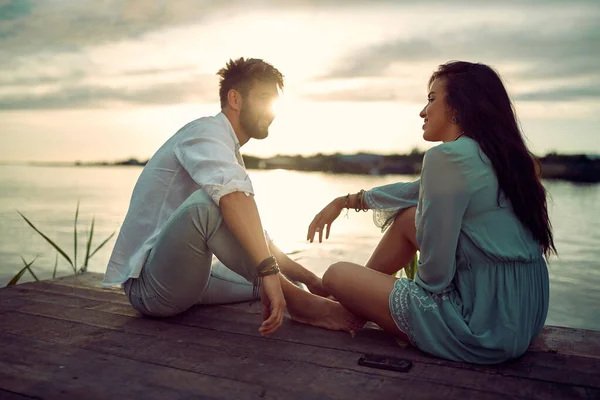 若いです男と女の愛でロマンチックな柔らかい瞬間を持っています川の上に日没 — ストック写真
