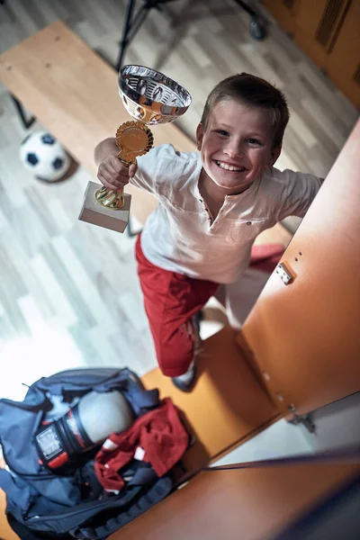 Een Kleine Voetballer Een Kleedkamer Opgewonden Gewonnen Beker — Stockfoto