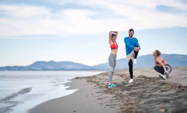 Bir grup arkadaş kumsalda birlikte esniyorlar.