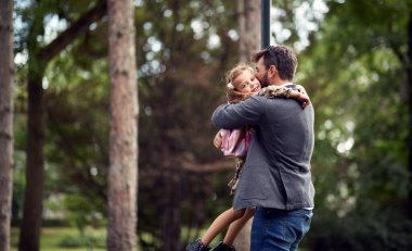 Baba okuldan sonra kızı parkta kucaklıyor.