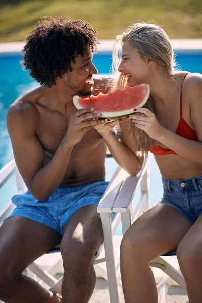 笑顔の男と女はスイミングプールの近くの夏休みを楽しみ スイカを食べる — ストック写真