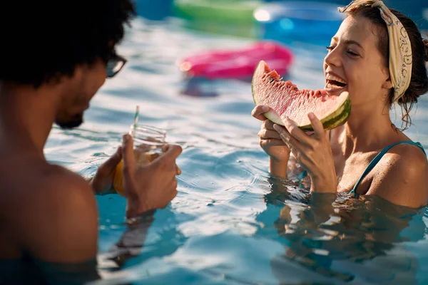 Smiling  couple  enjoy on summer holiday in swimming pool and  eating watermelon.