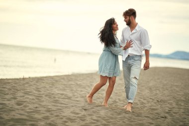 Romantik anlarda genç aşıklar sahilde güzel bir havada