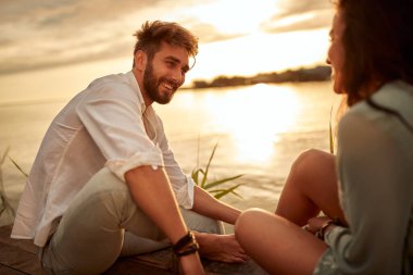 Genç çift ve gölün kıyısında romantik gün batımı