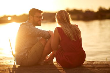 Romantik anlarda genç aşıklar gün batımında gölde güzel bir havada
