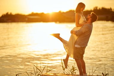 Mutlu genç çift gölde günbatımının tadını çıkarıyor.