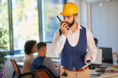 Genç mimar ofisteki telsizi kullanıyor.