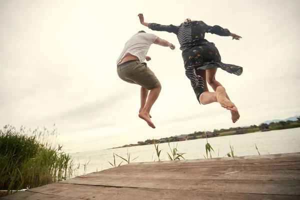 Casal Jovem Pulando Margem Lago Tempo Bonito — Fotografia de Stock