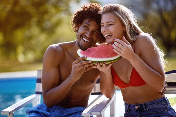 笑顔の男と女はスイミングプールの近くの夏休みを楽しみ スイカを食べる — ストック写真