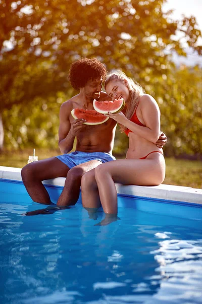 若い男と女の子はスイミングプールの近くの夏休みに楽しみ スイカを食べる — ストック写真