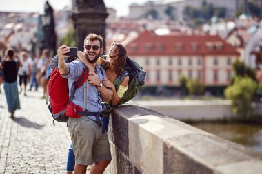 Gülümseyen gezginler aşık çiftler Prag şehrinin bir caddesinde yürürler ve selfie çekerler.. 