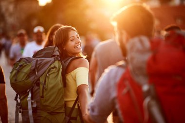 Günbatımında tatilin tadını çıkaran erkeklerle birlikte gülümseyen kadın. Seyahat, turizm ve insan konsepti.