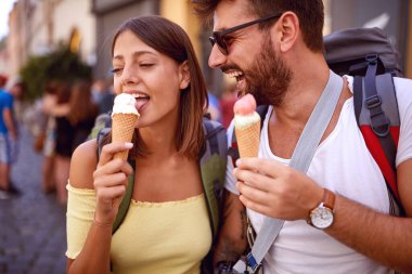 Genç turist çift güzel bir havada şehrin sokaklarında dondurma yiyor.