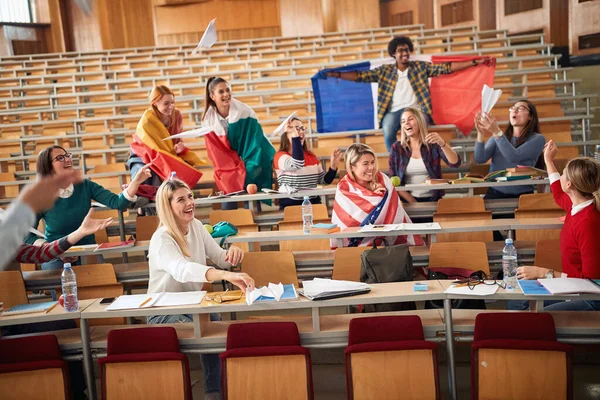 Happy students with flags in amphitheater together