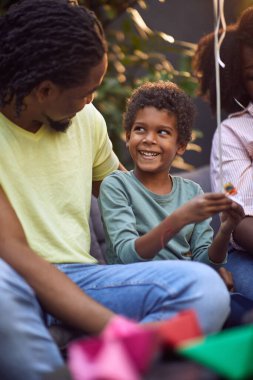 Genç Afro-Amerikalı çocuk babasıyla konuşuyor, ona bakıyor, gülümsüyor., 