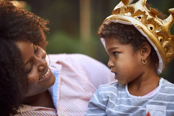 afro-american mother and daughter talking, smiling, looking each other