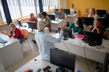 Üniversite bilgisayar sınıfında öğrencilerin sorularını açıklayan kadın profesör.