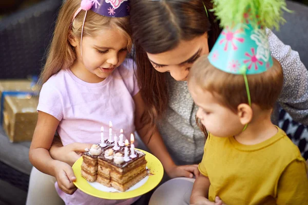 パーティーでろうそくと子供と誕生日ケーキを持つ若い白人女性のトップビュー — ストック写真