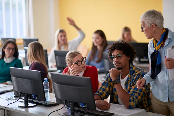 大学のコンピュータ教室で行われた情報学の講義で学生の質問に答える女性教授 — ストック写真