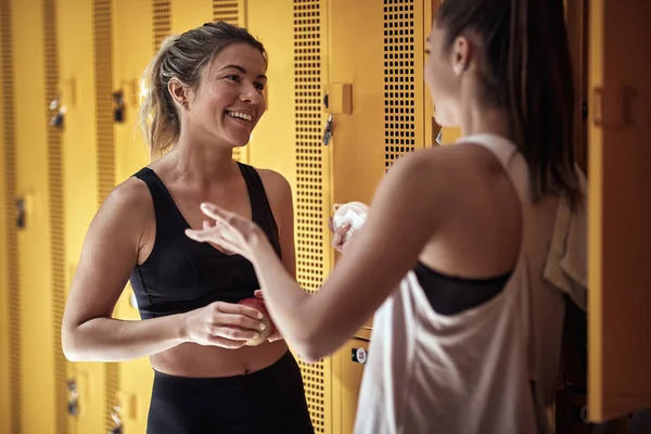 Female friends in friendly talk in a locker room after fitness