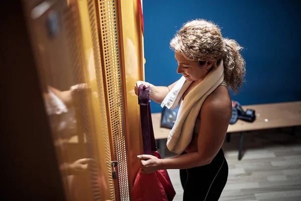 一个年轻的女运动员在更衣室里拿着训练用的装备 — 图库照片