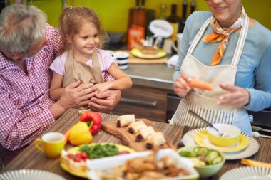 Torunum mutfakta büyükbabasının kucağında otururken büyükannem yemek yapıyor.