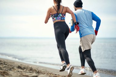 Genç bayan boksör ve koçu güzel bir havada sahilde koşuyorlar.