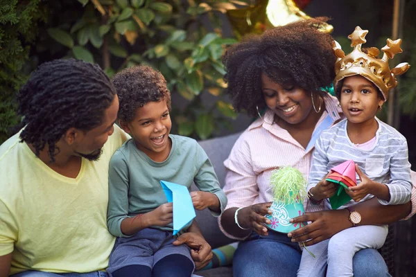 afro-american family gathered on birthday party, smiling, talking, playing with paper hat and boats
