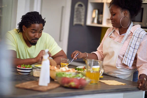 Cheerful Afro-American man and woman having diner in kitchen