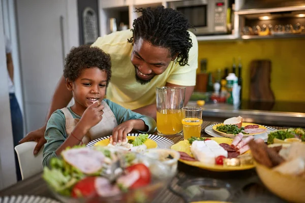 Afro-American male child with dad eating in kitchen