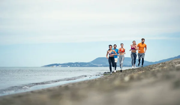 一群年轻人在美丽的天气里在岸上奔跑 — 图库照片