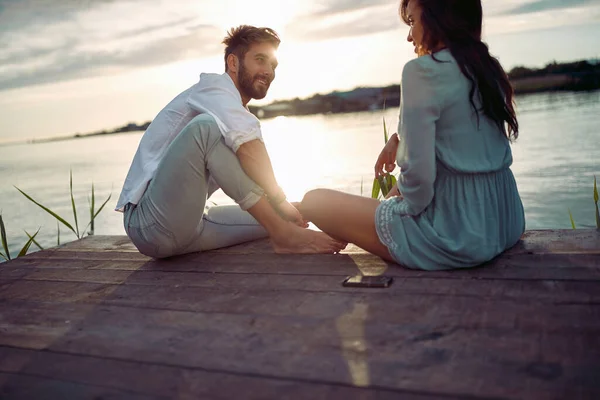 美しい天気の日に湖で夕日を楽しむ愛の若いカップル — ストック写真