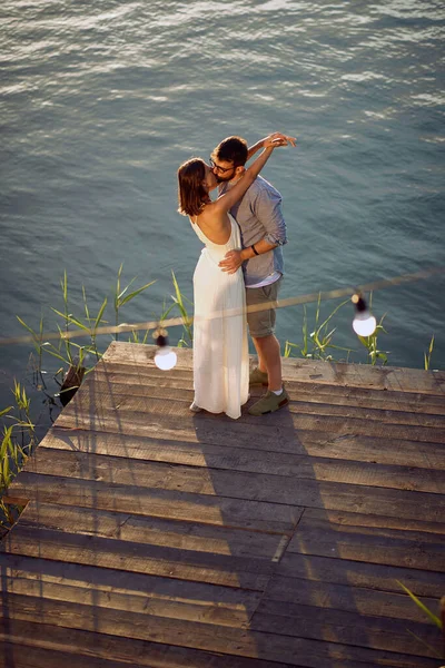 Young couple on the lake kissing in a love hug on a beautiful sunset