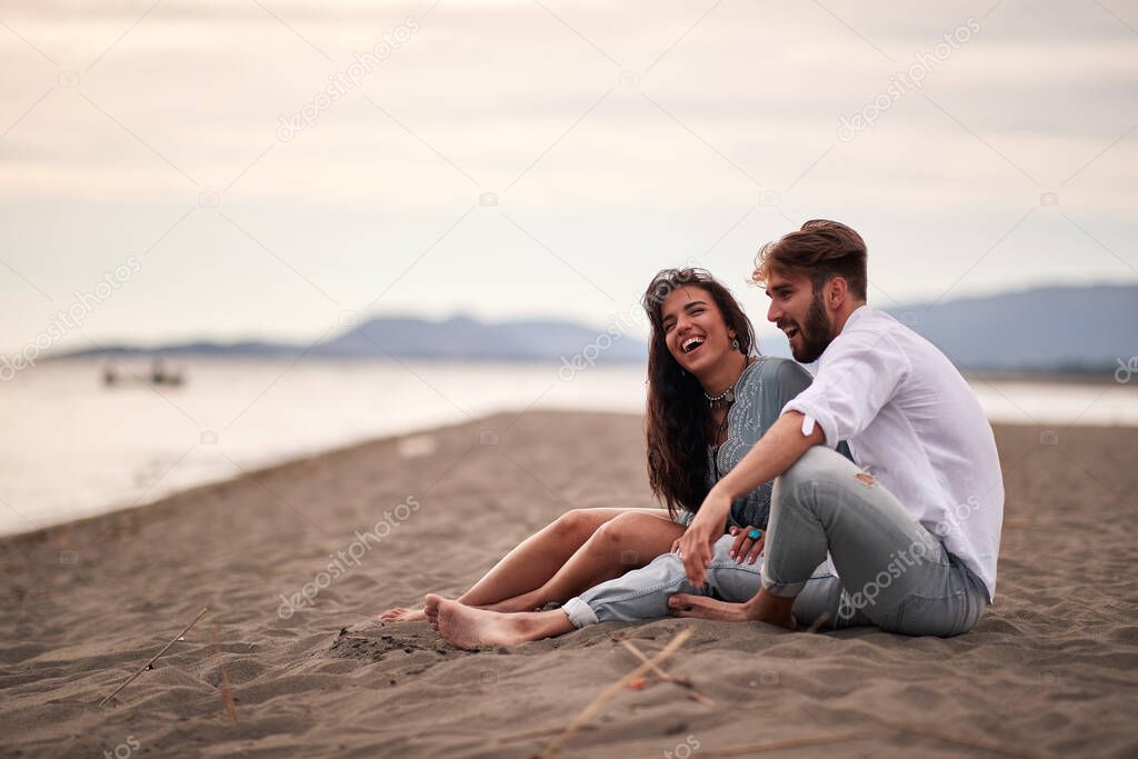 Young lovers sitting on the beach on a beautiful weather