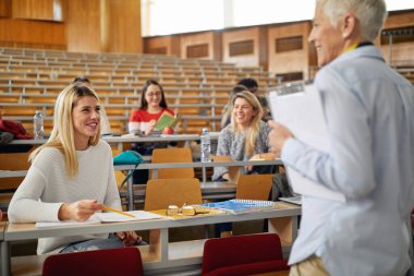 Bayan öğrenci üniversite amfitiyatrosunda profesörün dersini seviyor.