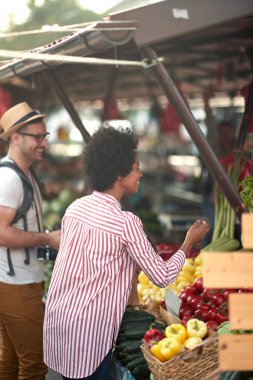 Yeşil pazarda ya da çiftçi pazarında taze ve organik sebze ve meyve satışı. Genç alıcılar markette sağlıklı yiyecekler için ürünler seçer ve satın alırlar. Hepsi diyet, sağlıklı beslenme ve yaşam tarzı için..