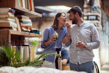 Kafe kütüphanesinde içki içen neşeli genç bir çift.