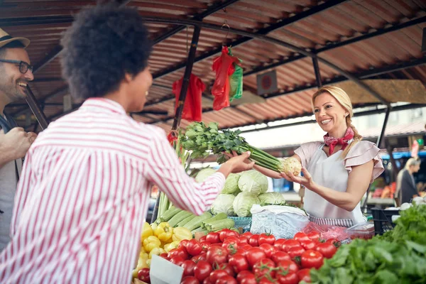 売り手の女性は 緑の市場や農家の市場の屋台で新鮮な有機野菜や果物を提供しています 若いバイヤーは食料品の健康な食糧のためのプロダクトを選び 健康的な食事 ライフスタイルのためのすべて — ストック写真