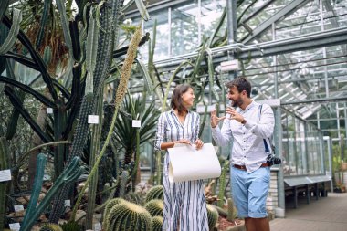 Genç bir adam botanik bahçesindeki bayan bir meslektaşına açıklama yapıyor.