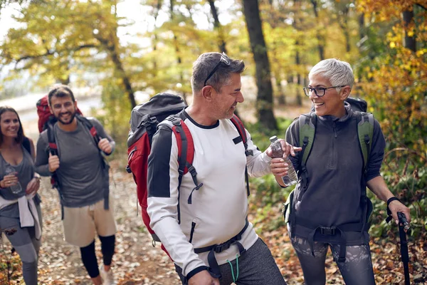 An elderly couple at hiking through the woods getting thirsty