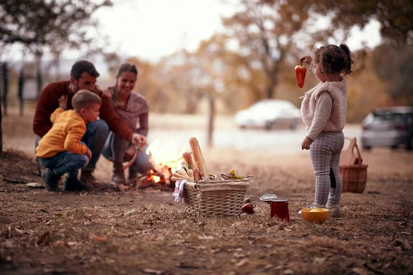 A happy family enjoying picnic and campfire in the forest on a beautiful autumn day