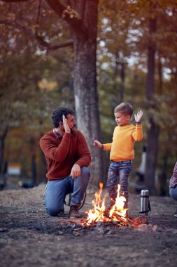 Baba ve oğul güzel bir sonbahar günbatımında ormanda başarılı bir kamp ateşi yaktılar.
