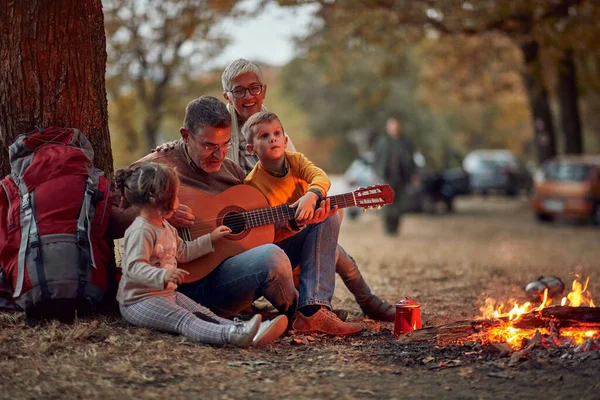 Starsza Para Wnuki Grają Gitarze Lesie Przy Ognisku Piękny Jesienny — Zdjęcie stockowe