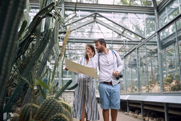Young colleagues observing cactuses by following a botanical garden map