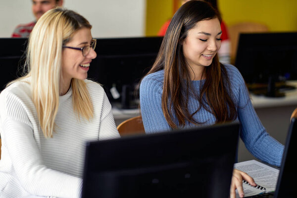 Female students enjoying an informatics lecture in the university computer classroom. Smart young people study at the college. Education, college, university, learning and people concept