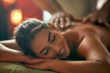 Çekici genç bir kadın uzanıyor ve rahatlıyor. Stüdyoda masajın keyfini çıkarıyor. Sağlık, sağlık, yaşam tarzı konsepti.