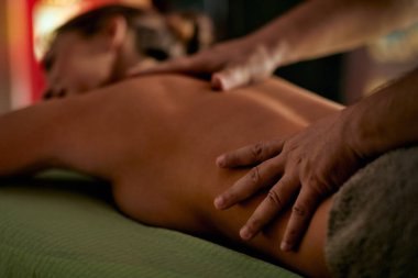 Masaj masasına uzanmış çekici genç bir kadın sağlık merkezindeki erkek terapistten tedavi görüyor. Sağlık, yaşam tarzı, rahatlama konsepti.