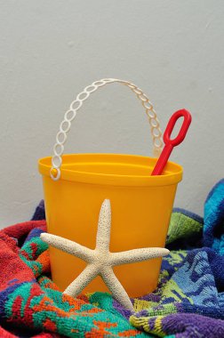 Bir havlu ile görüntülenen bir plastik kova. kürek ve bir deniz yıldızı
