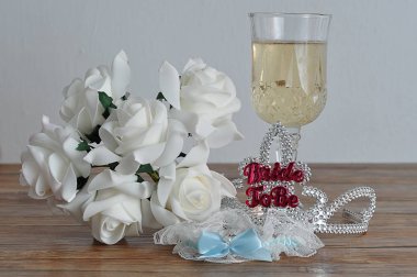 Bir kadeh şampanya, beyaz gül ve bir jartiyer ile görüntülenecek kelime gelinle bir taç
