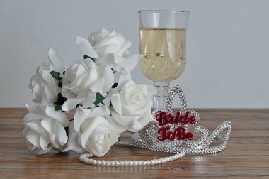 Bir kadeh şampanya, beyaz gül ve bir dizi inci ile görüntülenecek kelime gelinle bir taç